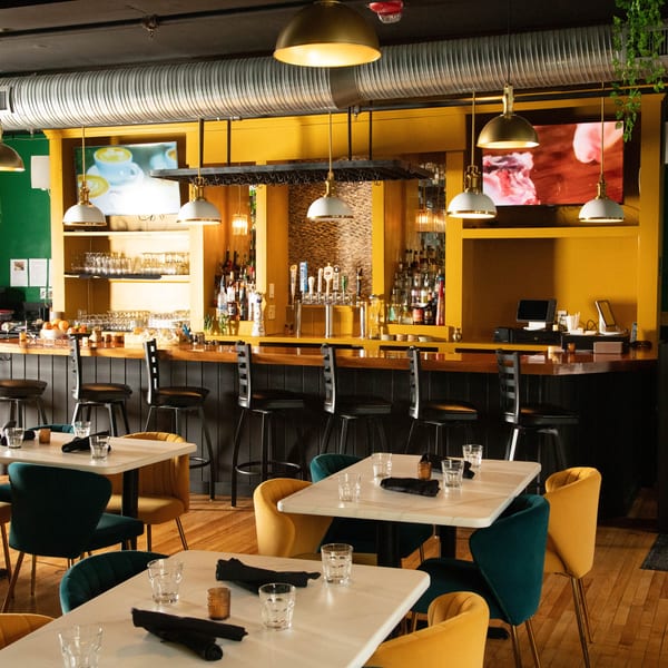 Bombay Bistro restaurant interior with a bar, dining tables, and yellow and green walls.